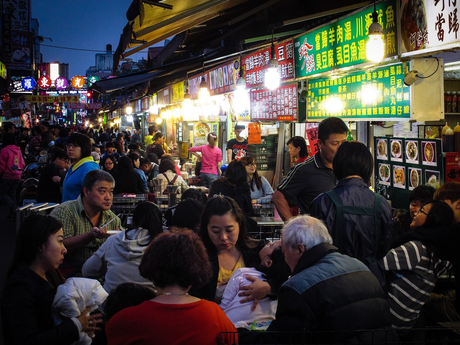 傍晚羅東夜市燈火通明的小吃攤前,坐滿用餐的客人